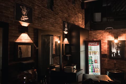 Lavatórios com luz âmbar, quadros da Barbearia Califórnia e geladeira de bebidas