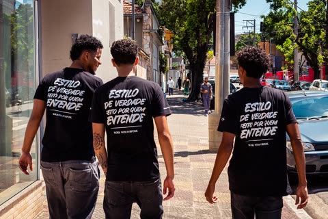 Barbeiros de costas na calçada com camisetas “Estilo de verdade”