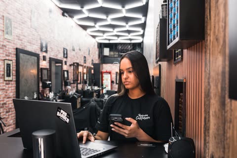 Recepcionista no balcão com o salão de paredes de tijolo ao fundo